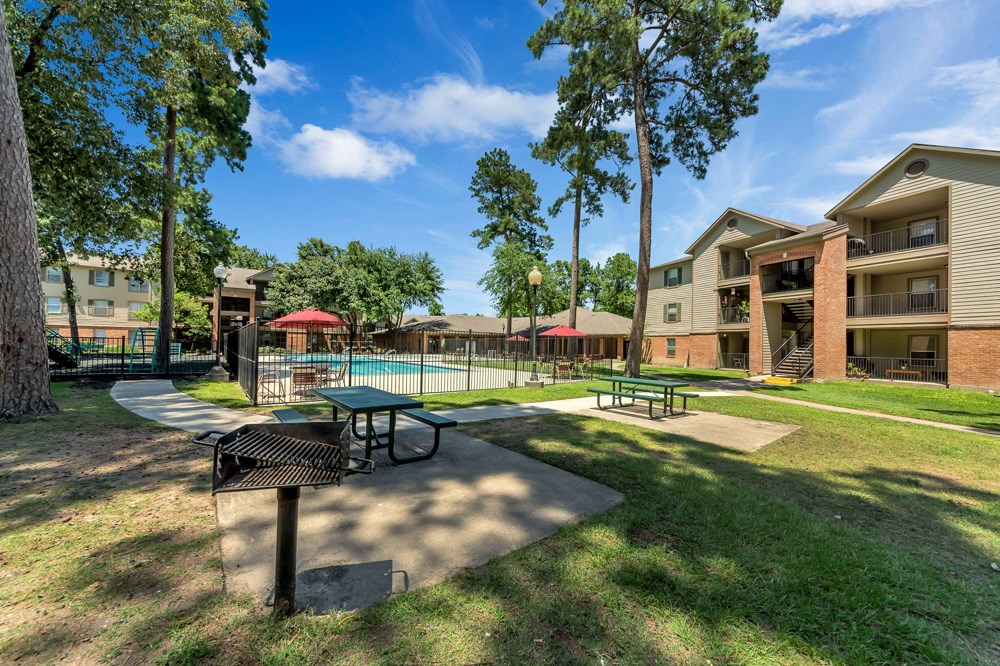 A sunny day at the apartment complex with a pool and picnic tables.