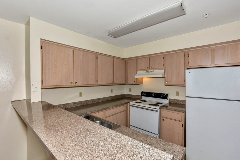 A kitchen with a white refrigerator and wooden cabinets.