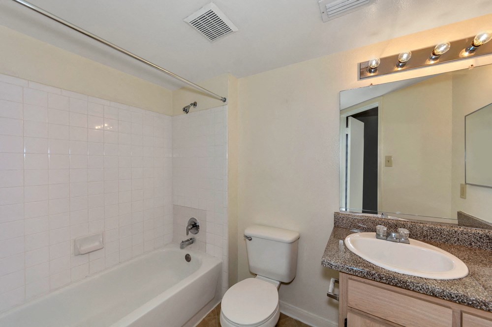 A white toilet sits next to a bathtub in a bathroom.