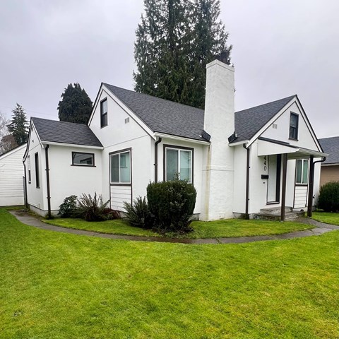 A white house with a black roof and a chimney.