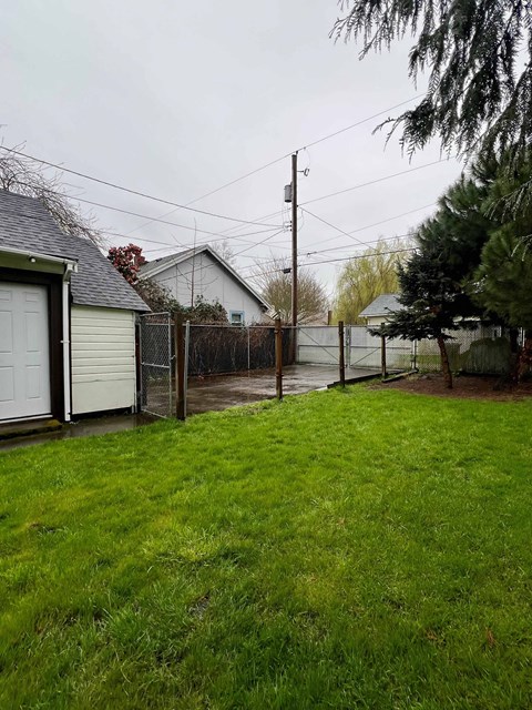 A grassy yard with a fence and a house in the background.