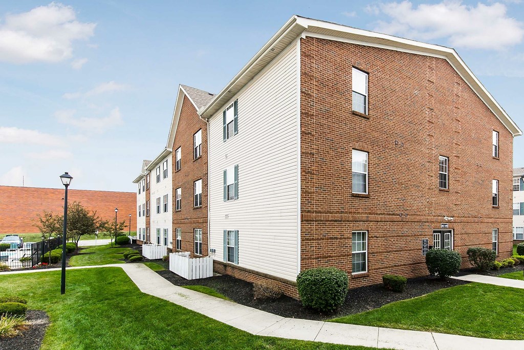 A red brick building with a white trim and a white fence in front of it.
