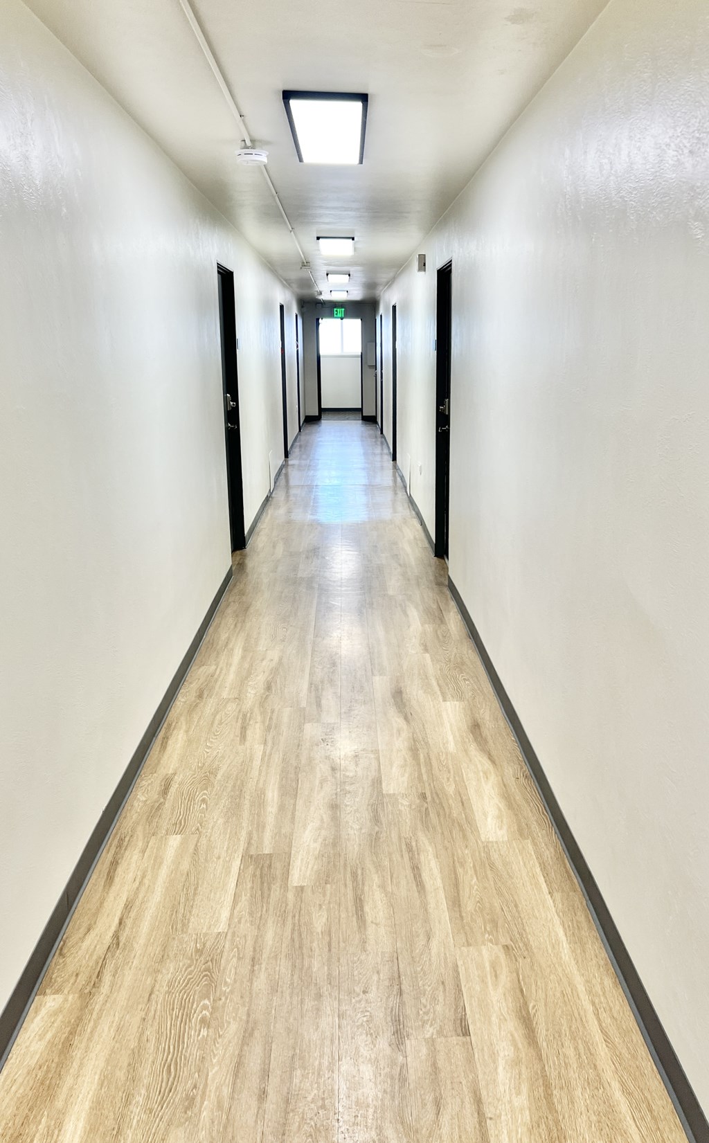 A long hallway with wood floors and white walls.