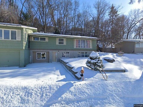 A person is shoveling snow in front of a house.
