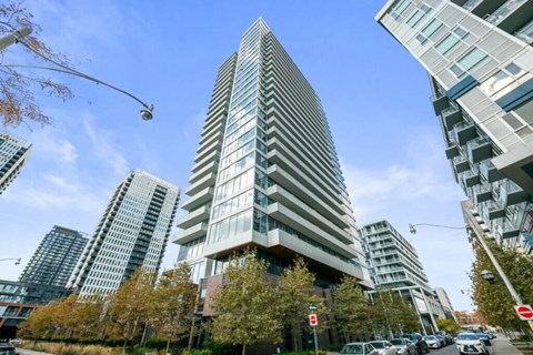 A tall building with a unique design stands out in a cityscape.