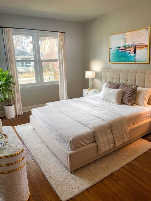 A bedroom with a large bed, a nightstand, and a painting on the wall.