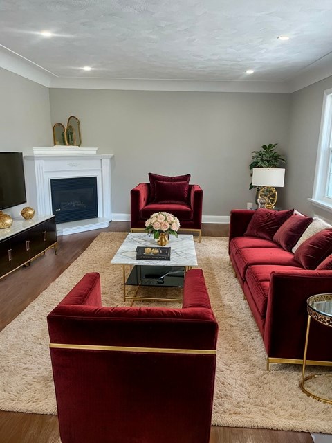 A living room with a red couch and a fireplace.
