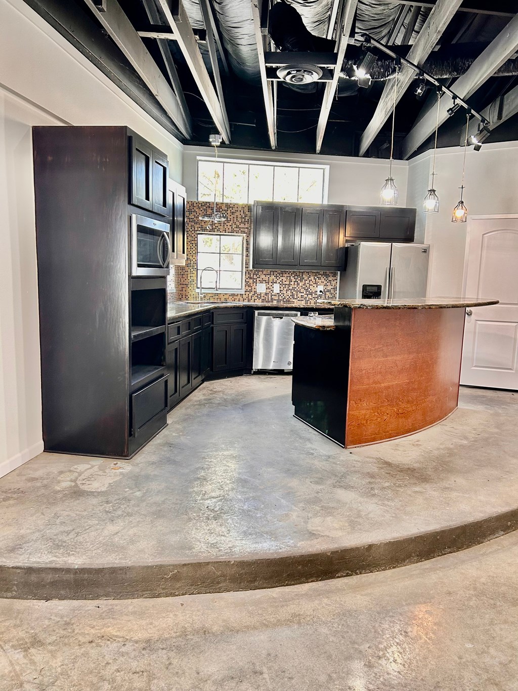 A kitchen with a curved counter and dark cabinets.