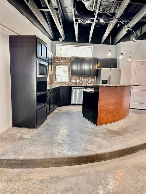 A kitchen with a curved counter and dark cabinets.