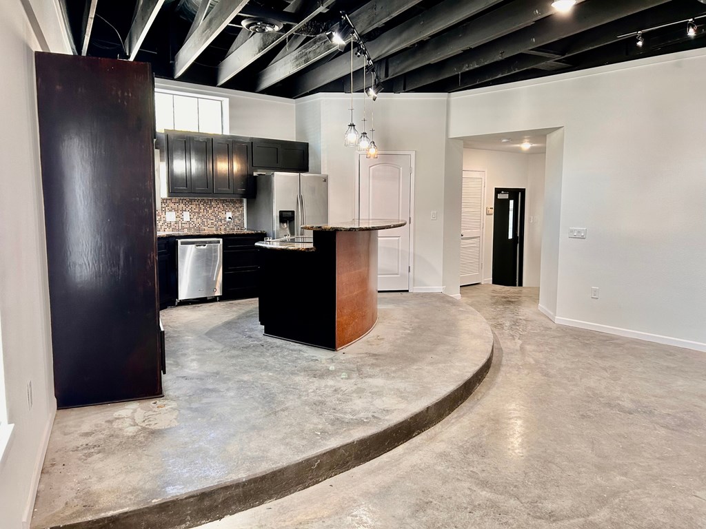 A kitchen area with a bar counter and a refrigerator.
