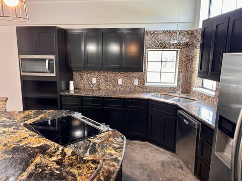 A kitchen with black cabinets and a granite countertop.