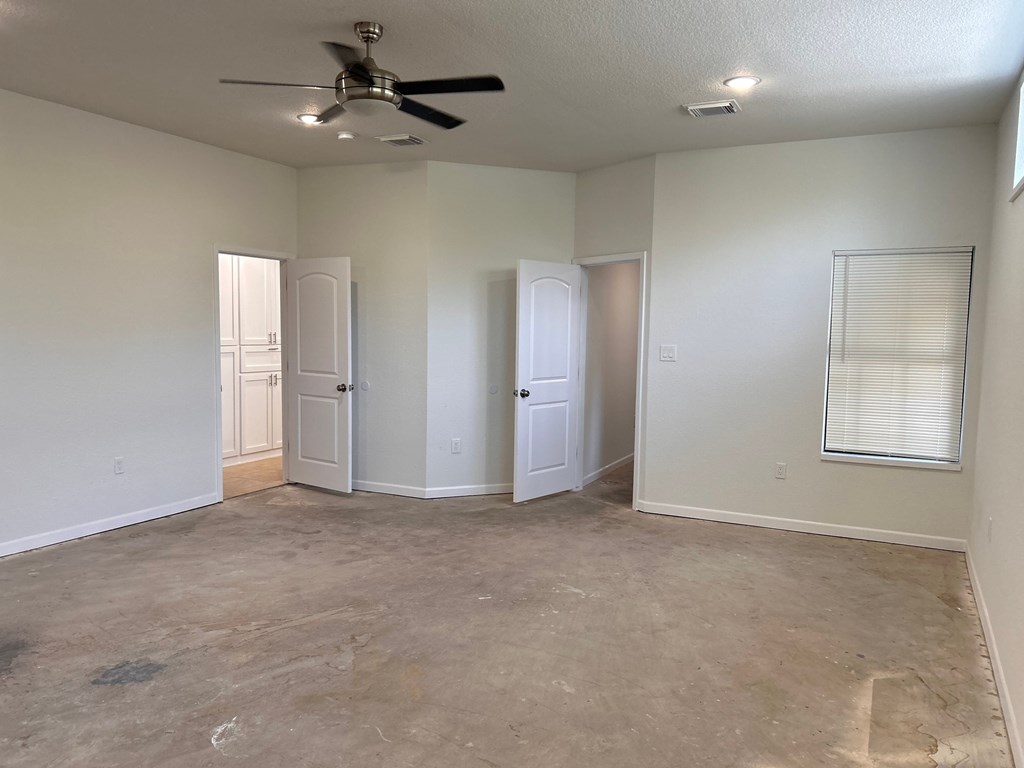 A room with a ceiling fan and three doors.