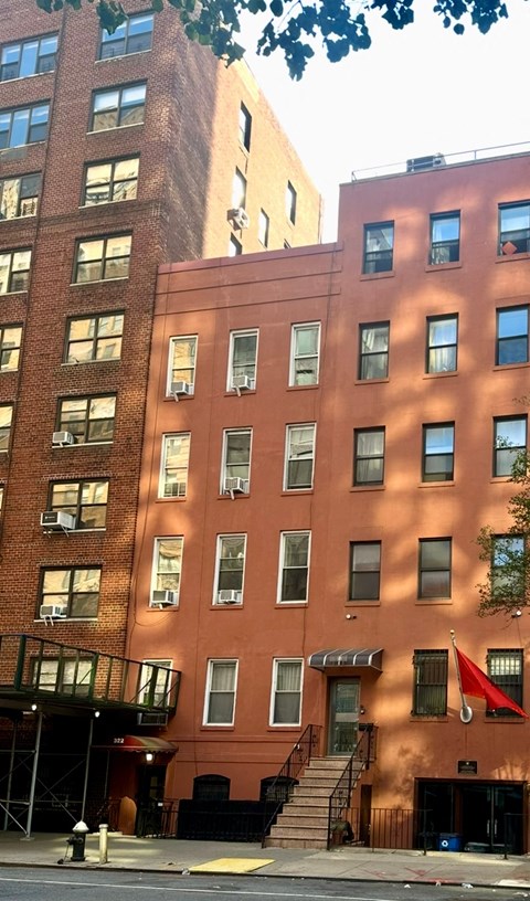 A red building with a balcony and stairs leading to it.