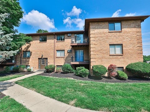 A brick apartment building with a green lawn in front.