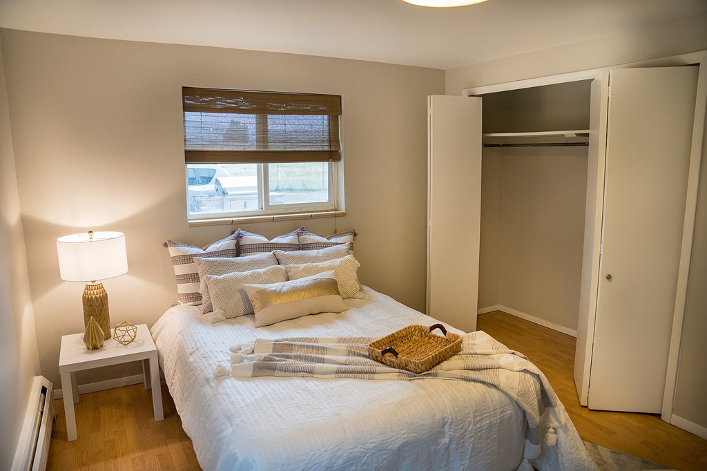 A bedroom with a bed, nightstand, and window.