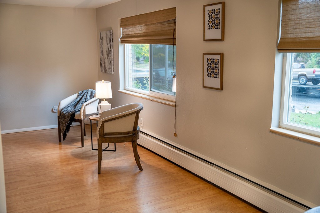 A chair sits in a corner of a room with a table and lamp.