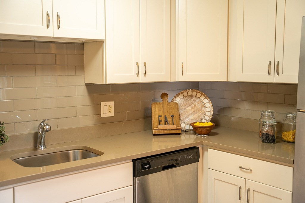 A kitchen with a stainless steel dishwasher and a wooden sign that says "EAT".