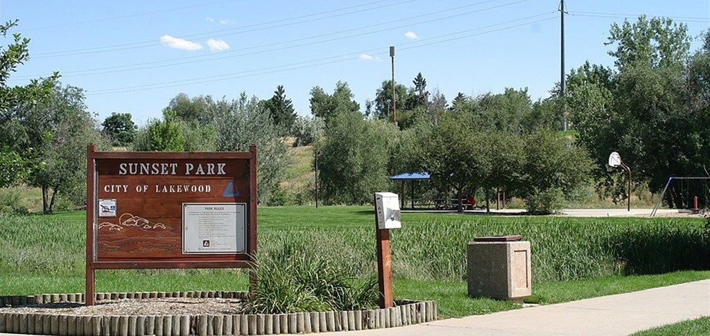 A sign for Sunset Park in the City of Lakewood stands in front of a field.