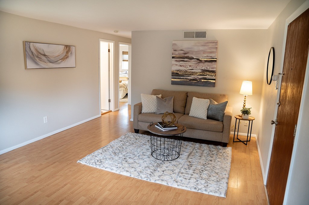 A living room with a couch, a coffee table, and a painting on the wall.
