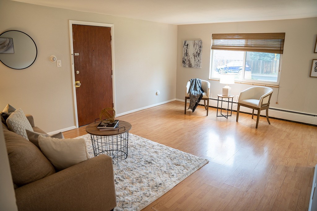 A living room with a brown couch, a coffee table, and a window with blinds.