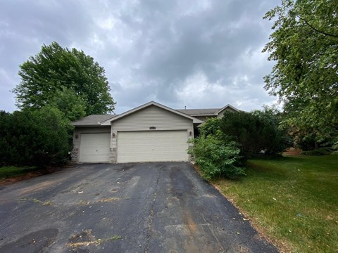 A house with a grey roof and two garage doors.
