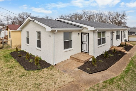 A white house with a black door and a small front yard.
