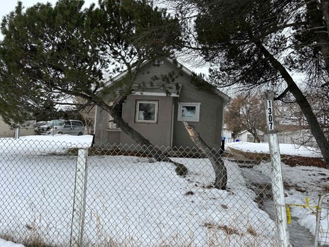 A small house is surrounded by a chain link fence.