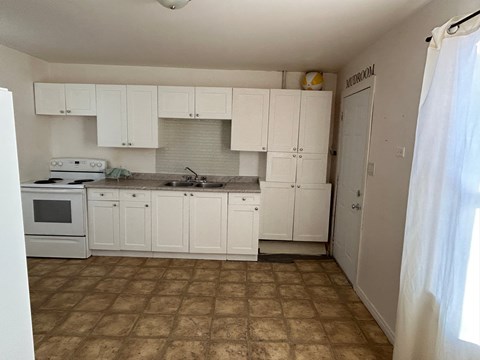 A kitchen with white cabinets and a tiled floor.