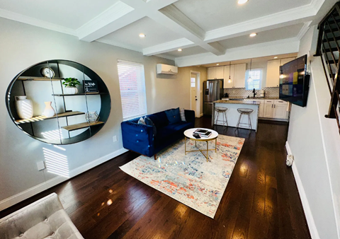A living room with a blue sofa and a round mirror on the wall.