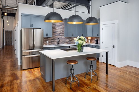 A kitchen with a white island and a vase of flowers on it.