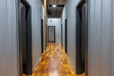 A long corridor with doors on both sides and a wooden floor.