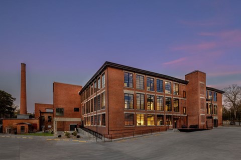 A large red brick building with a parking lot in front.