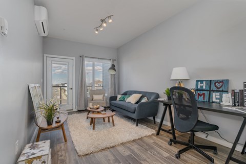 A living room with a grey couch, a wooden coffee table, and a black chair.