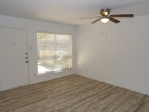 A room with a ceiling fan and a window with blinds.