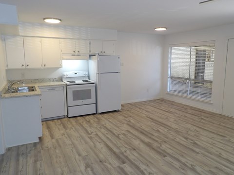 A kitchen with white appliances and wooden floors.