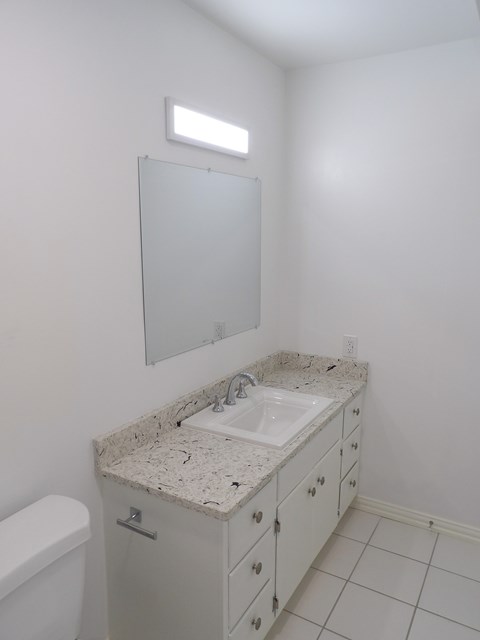 A bathroom with a sink, toilet, and mirror.