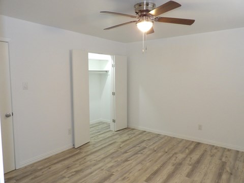 A room with a ceiling fan and wooden flooring.