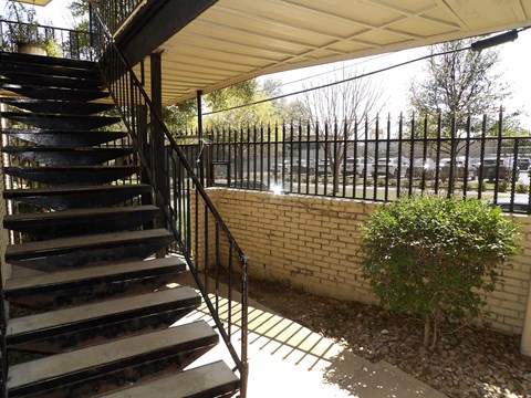 A staircase with a metal railing and a brick wall.