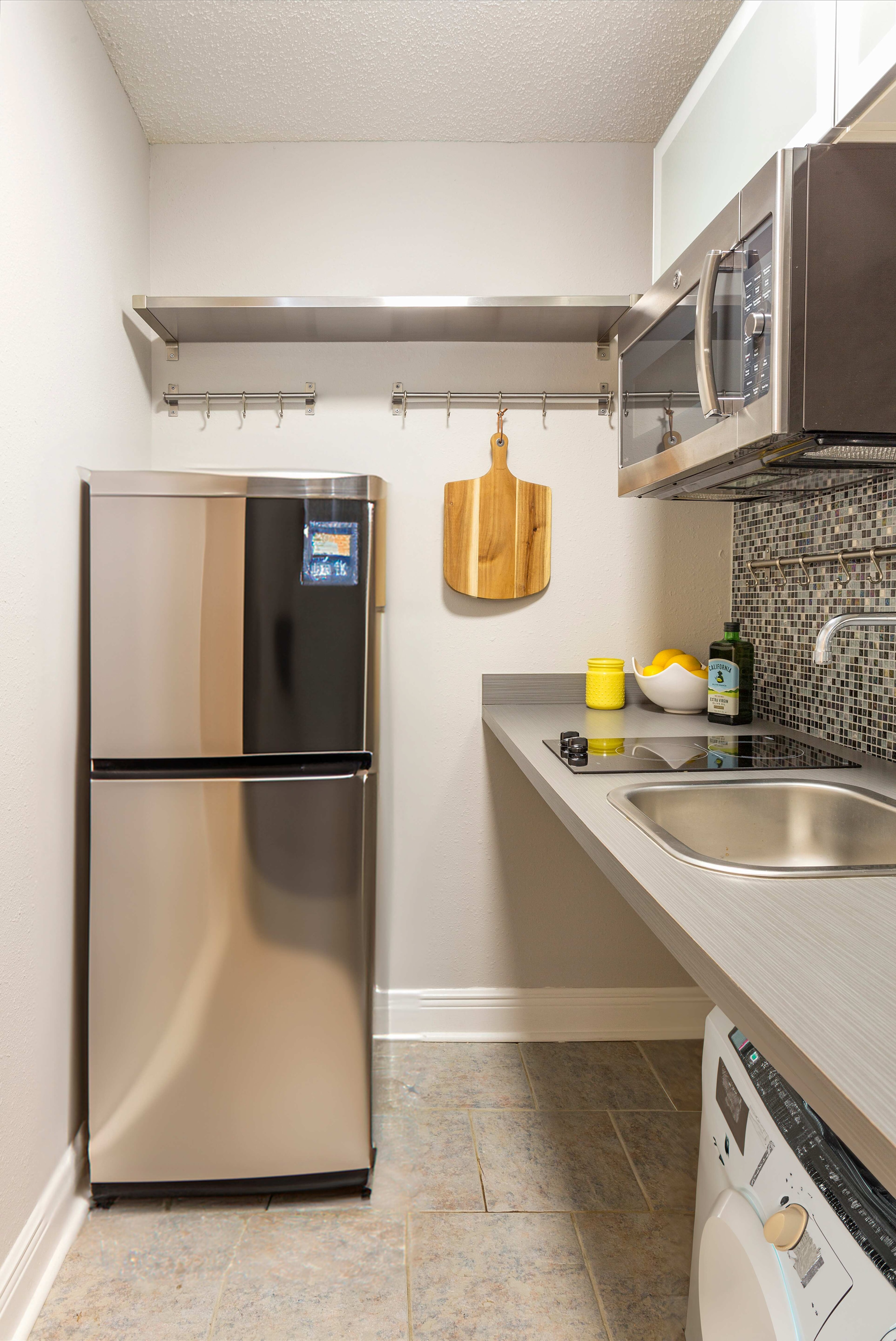 A kitchen with a stainless steel refrigerator and a microwave above the stove.