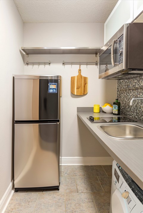 A kitchen with a stainless steel refrigerator and a microwave above the stove.