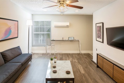 A living room with a black couch and a ceiling fan.