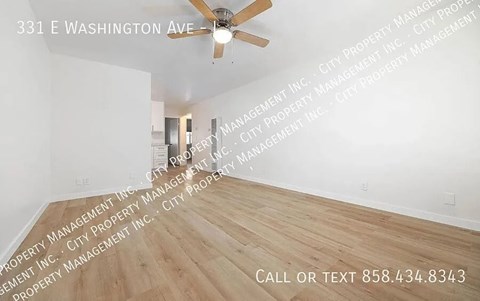 A room with a ceiling fan and wooden flooring is shown with a watermark of a property management company.