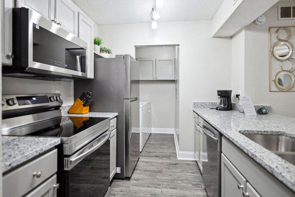 A kitchen with a refrigerator, stove, and microwave.