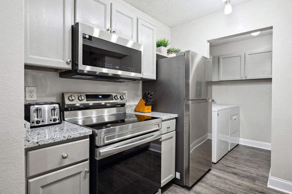 A kitchen with a stainless steel refrigerator, oven, and microwave.