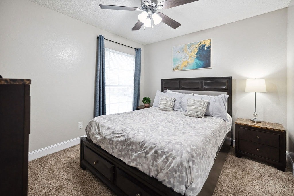 A bedroom with a bed, nightstand, and a ceiling fan.