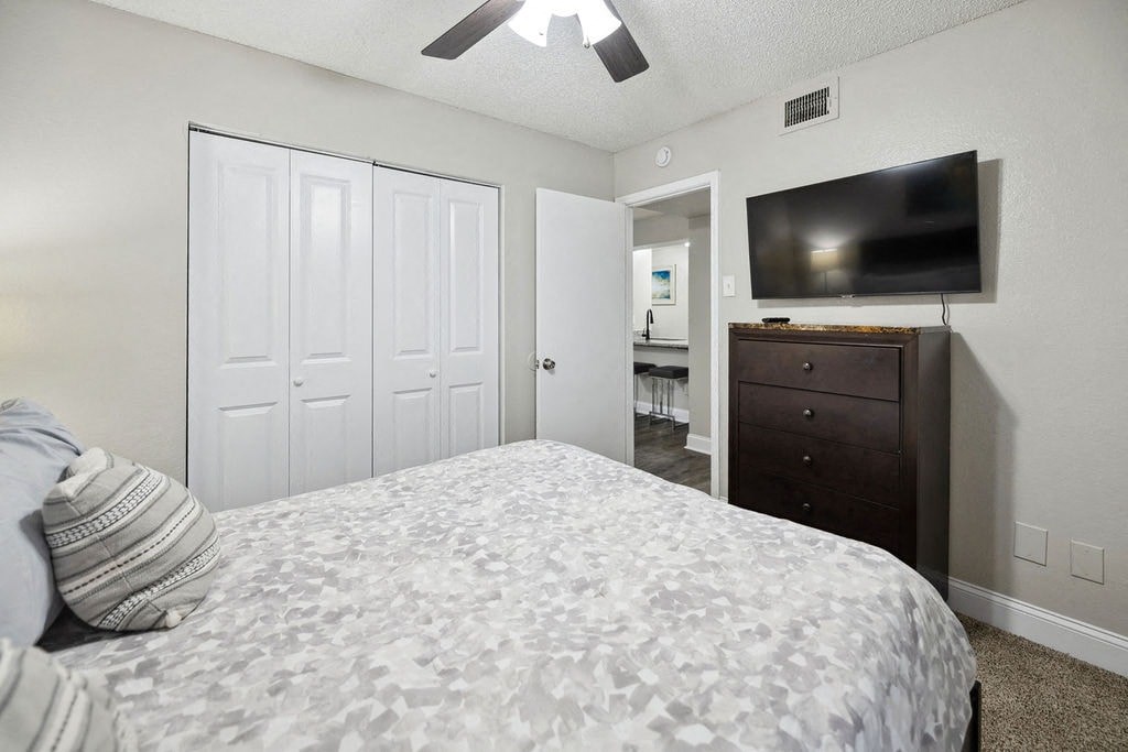 A bedroom with a bed, dresser, and television.