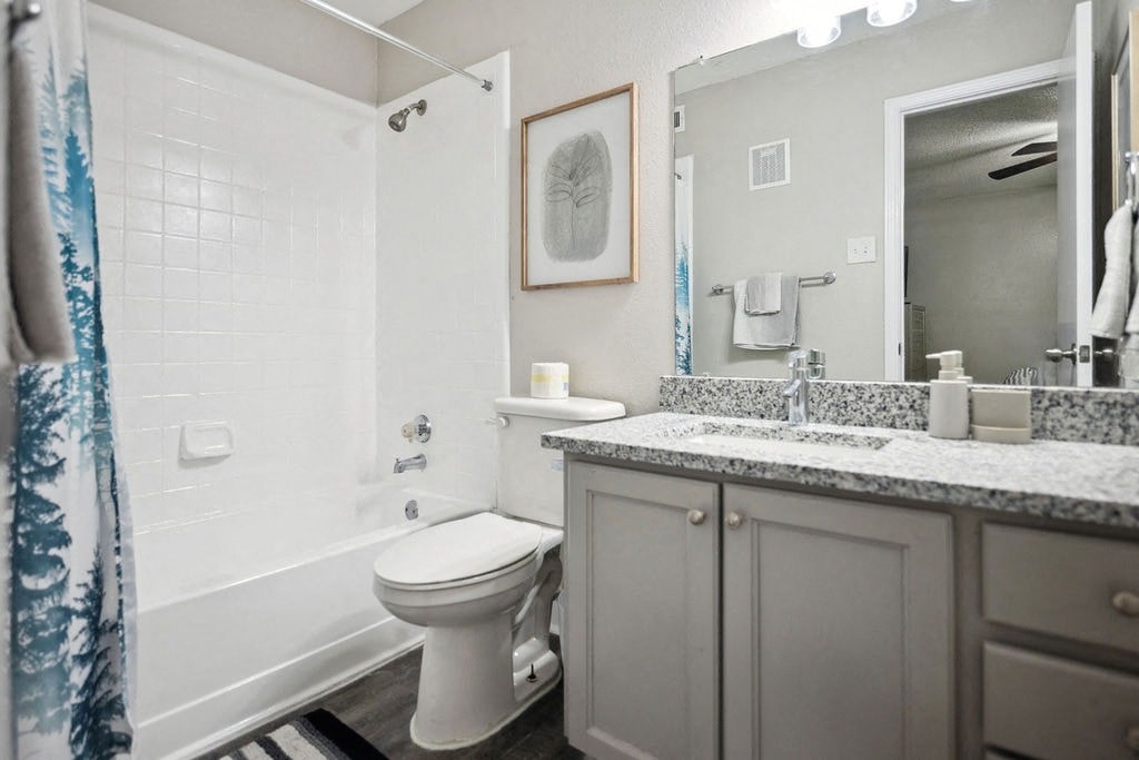 A white toilet sits in a bathroom with a white shower curtain.