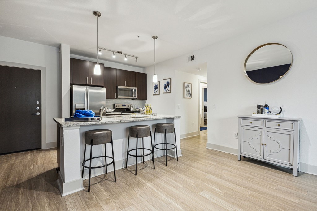 A kitchen with a bar area and a fridge at Everra Midtown Park Apartments, Dallas 75231