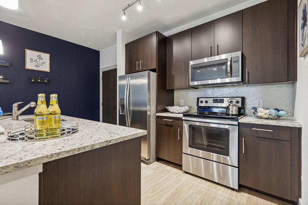 A kitchen with a stove top oven and a refrigerator at Everra Midtown Park Apartments, Dallas, Texas
