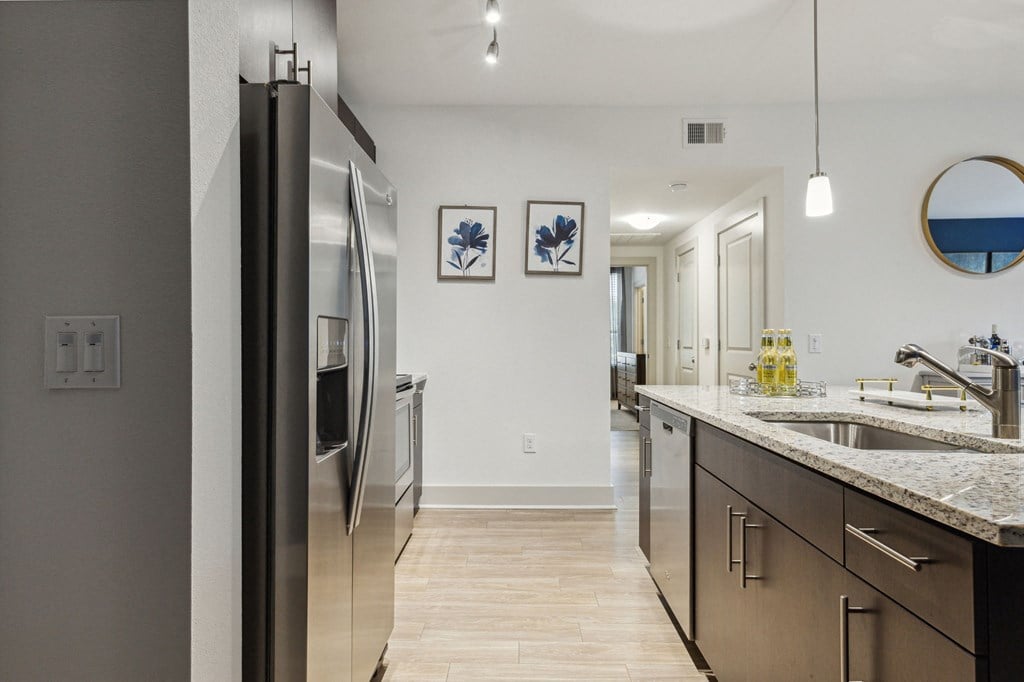 A kitchen with a refrigerator, sink, and cabinets at Everra Midtown Park Apartments, Dallas